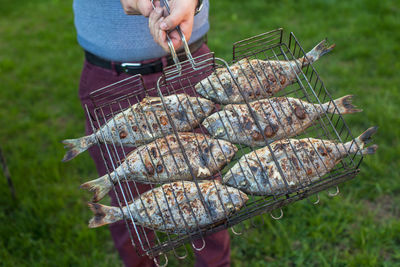 Midsection of person preparing meat on barbecue grill