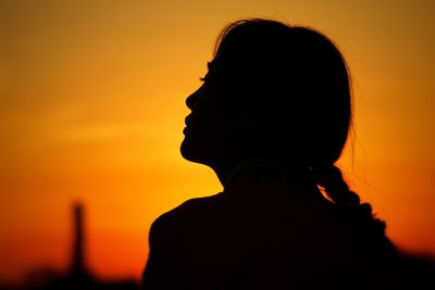 Close-up portrait of silhouette woman against orange sky