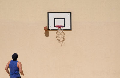 Man playing basketball against wall