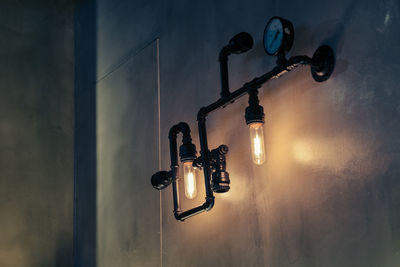 Low angle view of illuminated light bulb against wall