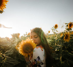 Side view of young woman standing by plants