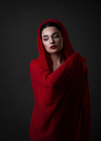 Portrait of beautiful young woman against black background