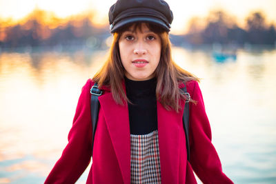 Portrait of beautiful young woman standing against lake