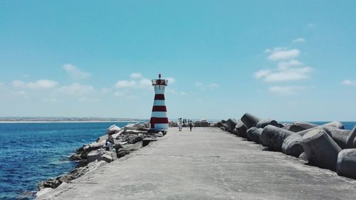 Lighthouse by sea against sky