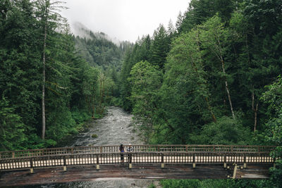 A young couple enjoys a hike on a boardwalk in the pacific northwest.