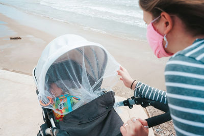 Mother wearing mask with baby on beach