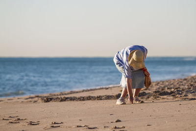 Low section of man standing on beach against clear sky