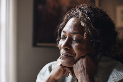 Mature woman with eyes closed day dreaming at home