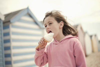 Girl licking ice cream cone at beach