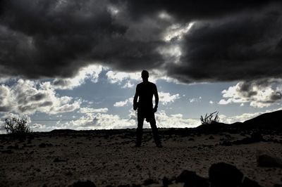 Silhouette man standing on sand dune in desert