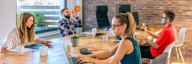 Businessmen having fun playing with a basket ball in coworking office