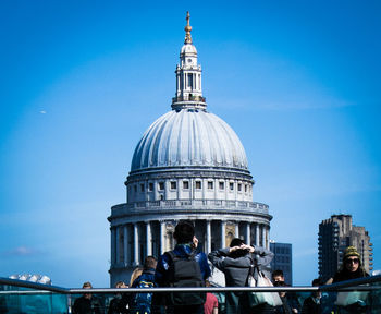 Tourists in front of building against blue sky