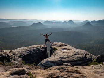 Shirtless male silhouette with raised arms on mountain top. sport life concept outdoor activities