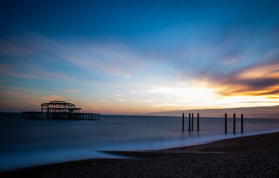 Pier over sea against sky during sunset