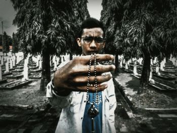 Portrait of young man standing against trees