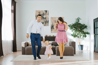 Happy young parents teach their daughter to walk. baby's first steps