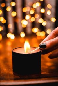 Close-up of hand holding illuminated candle