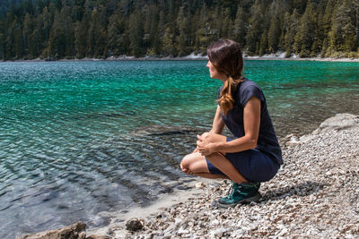 Side view of young woman standing at lakeshore