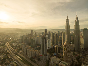 Petronas towers and modern buildings in city during sunrise