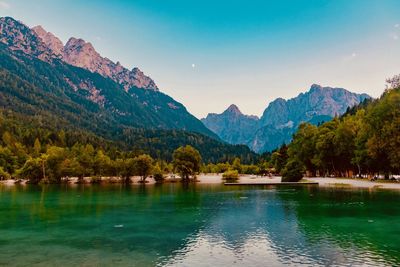 Scenic view of lake by mountains against sky