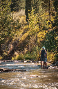 Rear view of men fishing while standing in river