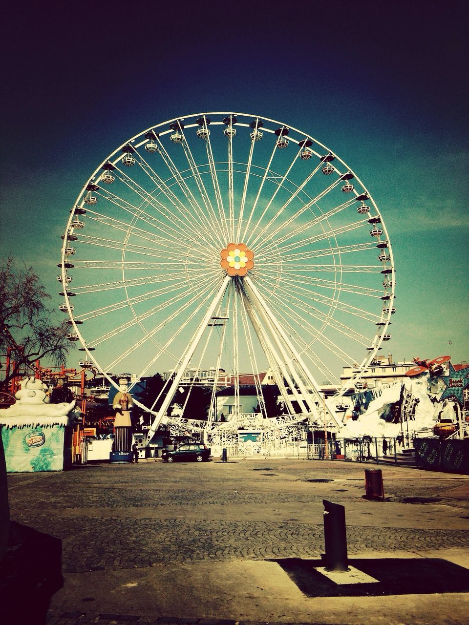 ferris wheel, amusement park, amusement park ride, arts culture and entertainment, circle, sky, low angle view, built structure, outdoors, large, clear sky, fun, day, tree, incidental people, metal, no people, architecture, geometric shape, big wheel