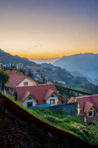 Houses in town against sky during sunset