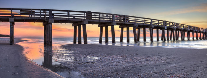 Bridge over sea against sky during sunset