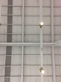 Low angle view of illuminated light bulbs hanging on ceiling in building