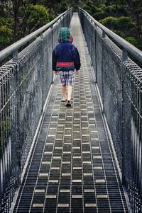 Boy walking on footbridge