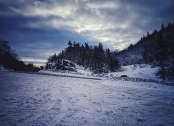 Snow covered land and trees against sky