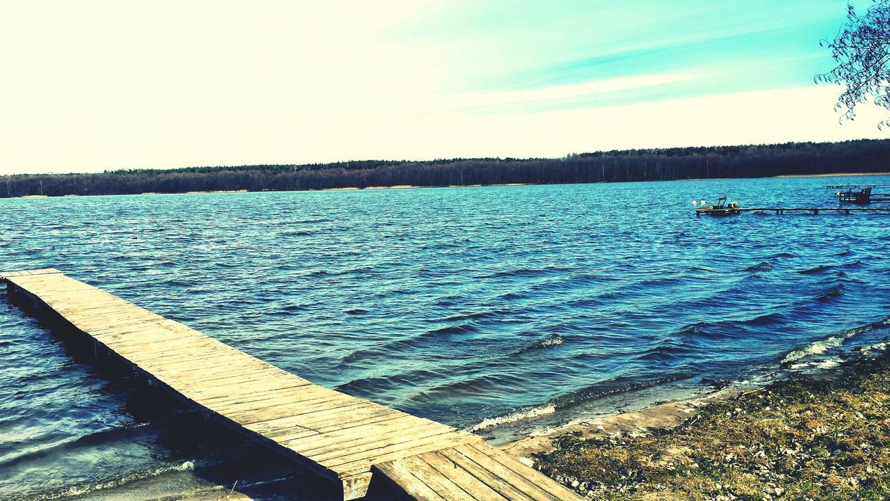 water, tranquil scene, tranquility, blue, scenics, pier, sea, sky, beauty in nature, nature, rippled, lake, wood - material, idyllic, tree, jetty, day, railing, outdoors, calm