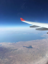 Airplane flying over landscape against blue sky
