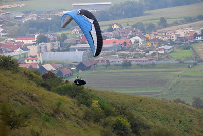 Paraglider flying over mountain in town