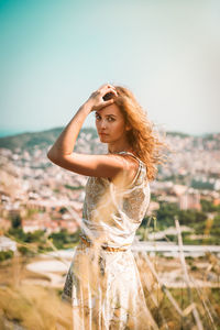 Young woman with arms raised standing against sky