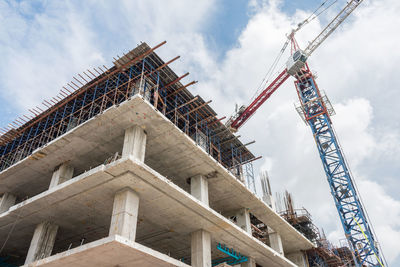 Low angle view of crane at construction site against sky