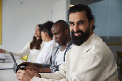 Smiling man sitting during business meeting and looking at camera