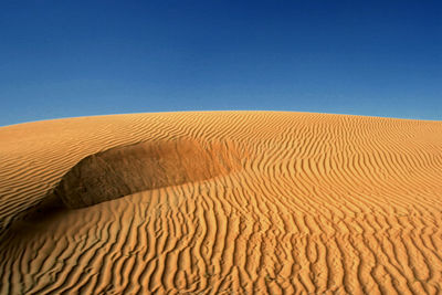 Scenic view of sand dunes against clear blue sky