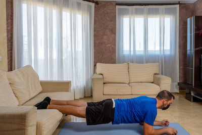 Man exercising with face mask on mat at home