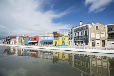 Buildings by river against sky in city