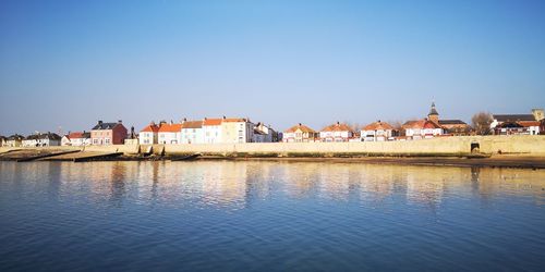 Buildings by town against clear blue sky