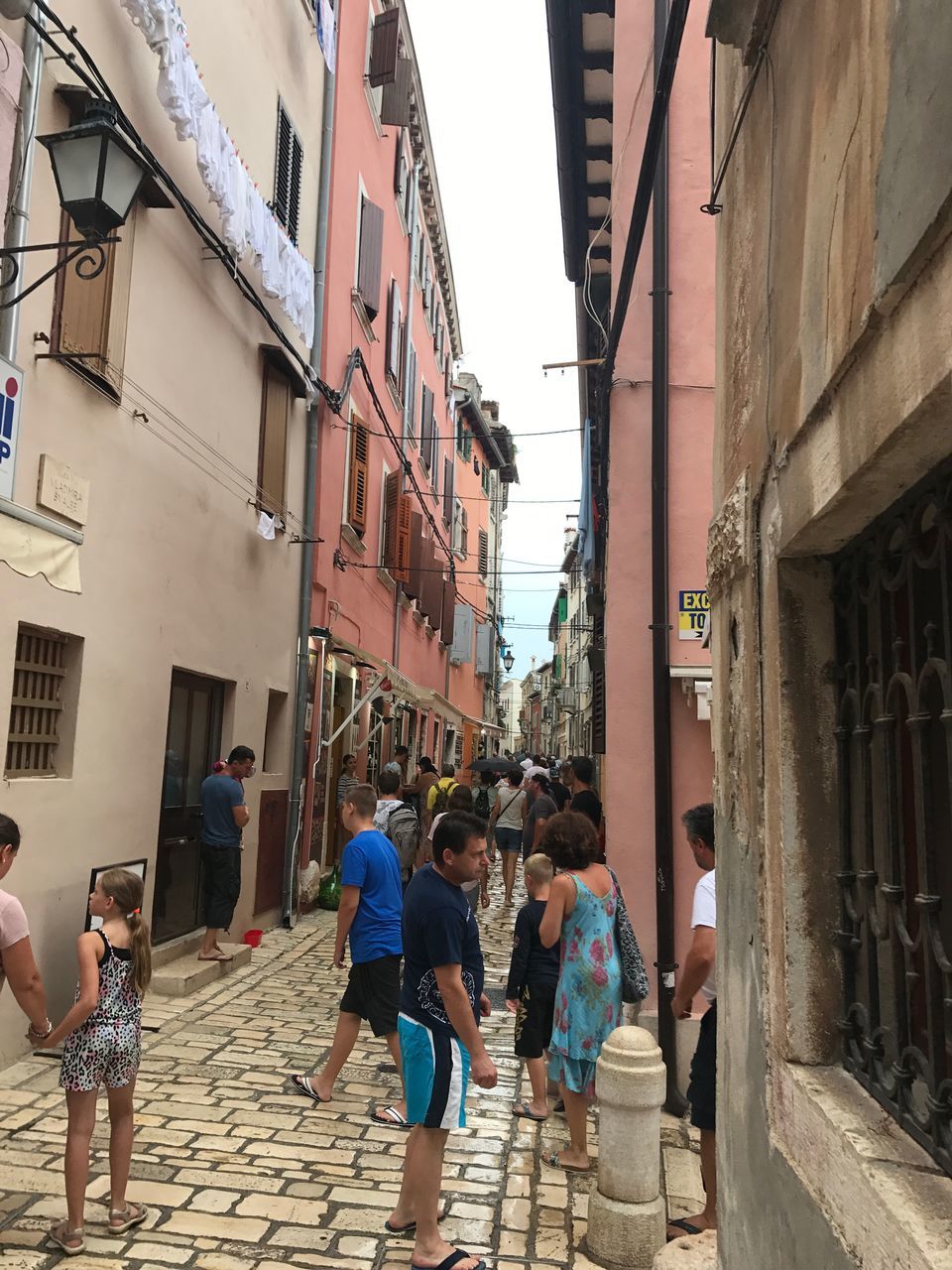 PEOPLE WALKING ON STREET AMIDST BUILDINGS