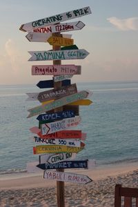 Information sign on beach against sky