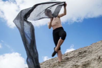 Low angle view of woman with arms raised against sky