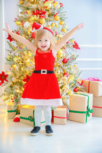 Full length of cute girl with red christmas tree