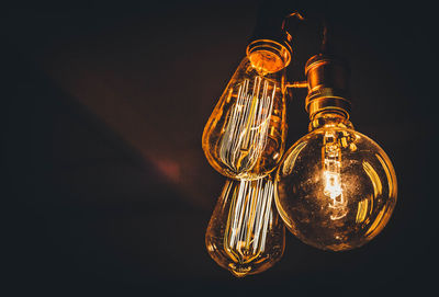 Low angle view of illuminated light bulbs hanging from ceiling