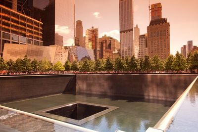 Buildings by swimming pool in city against sky