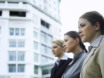 Young businesswoman with colleagues standing by building