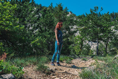 Woman standing by tree in forest