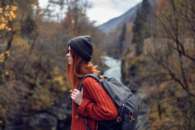 Side view of young woman standing in forest during autumn